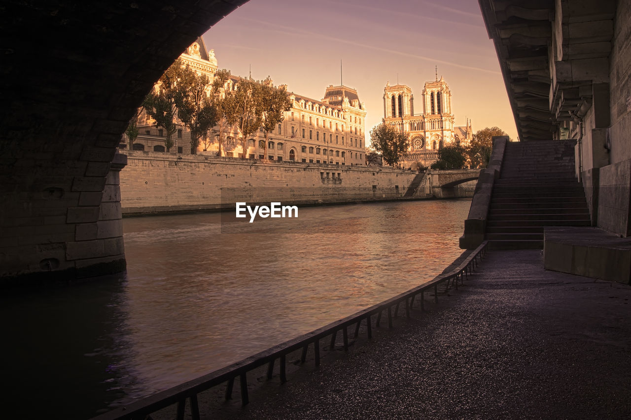 BRIDGE OVER RIVER AMIDST BUILDINGS IN CITY