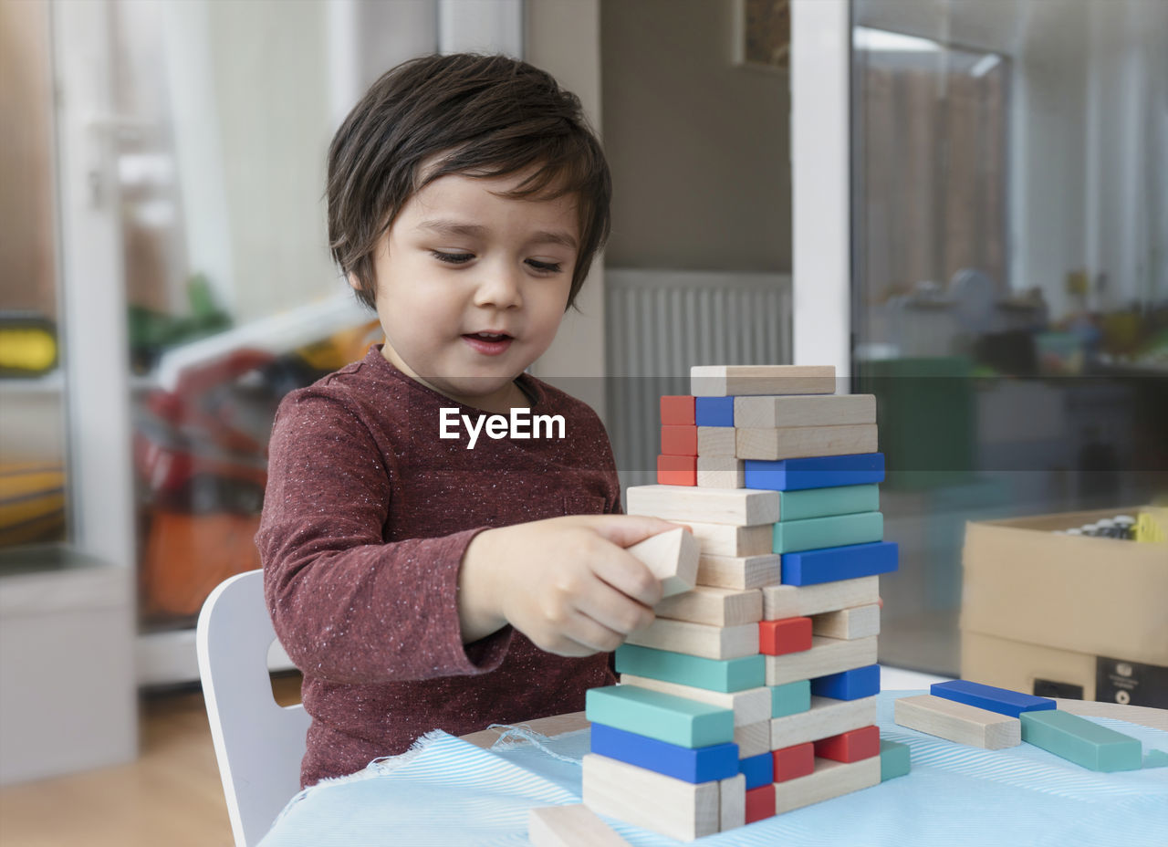 Close-up of cute boy playing with wooden blocks on table