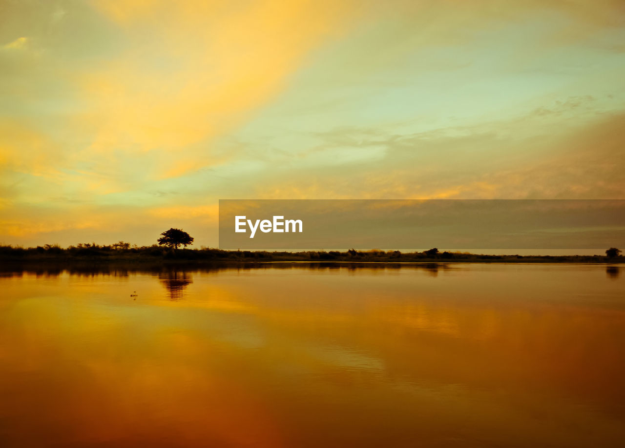 Scenic view of lake against orange sky during sunset