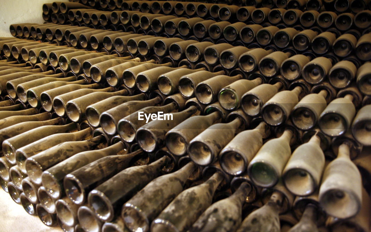 Stack of dust covered wine bottles in warehouse