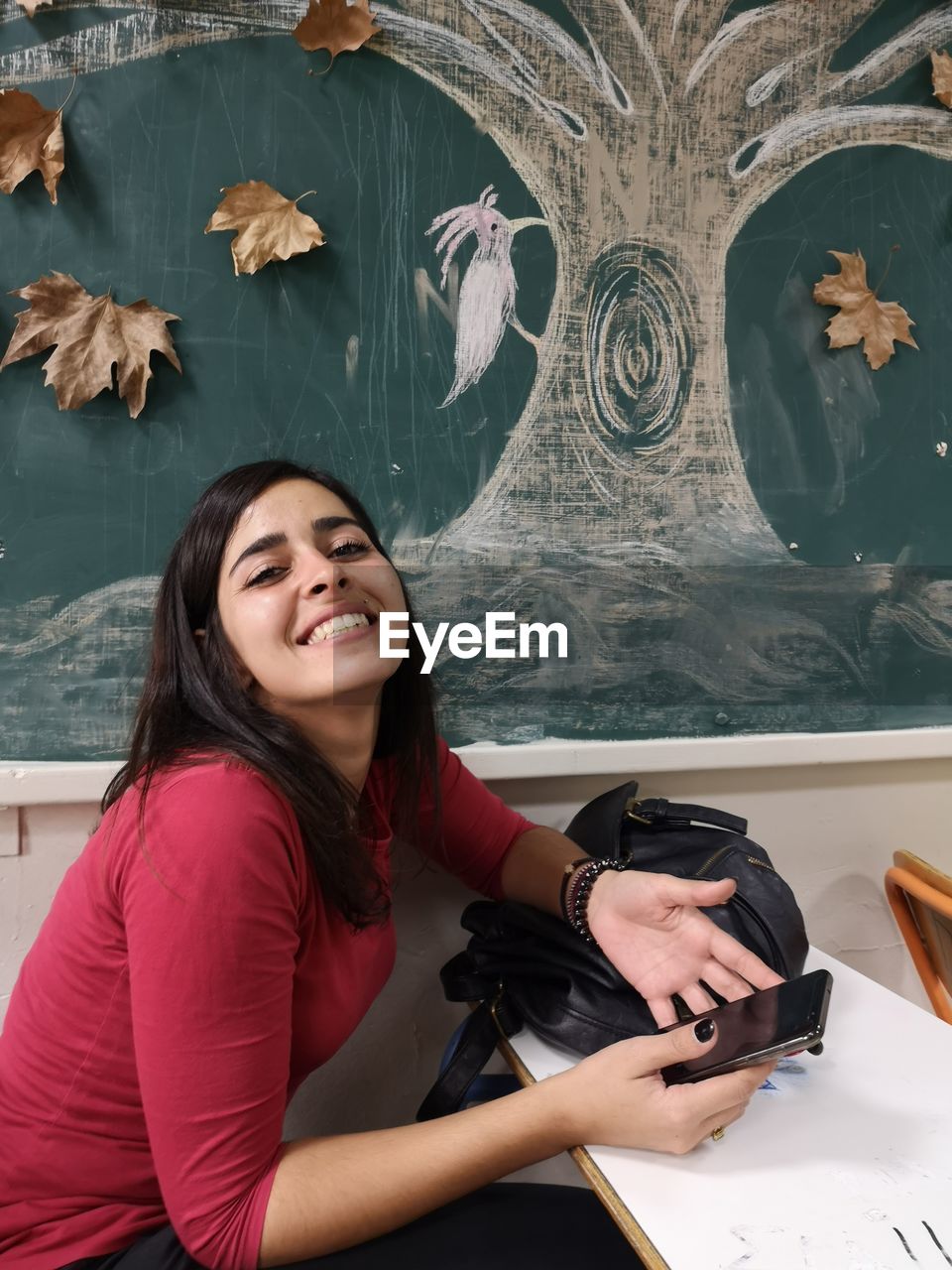 Portrait of smiling young woman using mobile phone on table