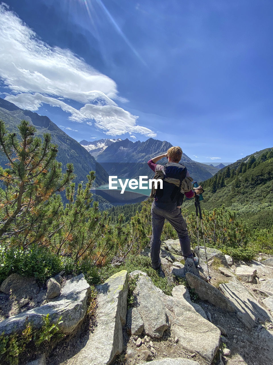 Rear view of a person overlooking the reservoir against mountain range and blue sky