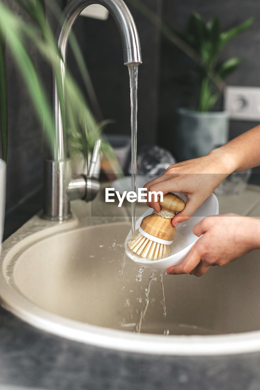 Close-up of child's hands washing dishes with eco dish brush.