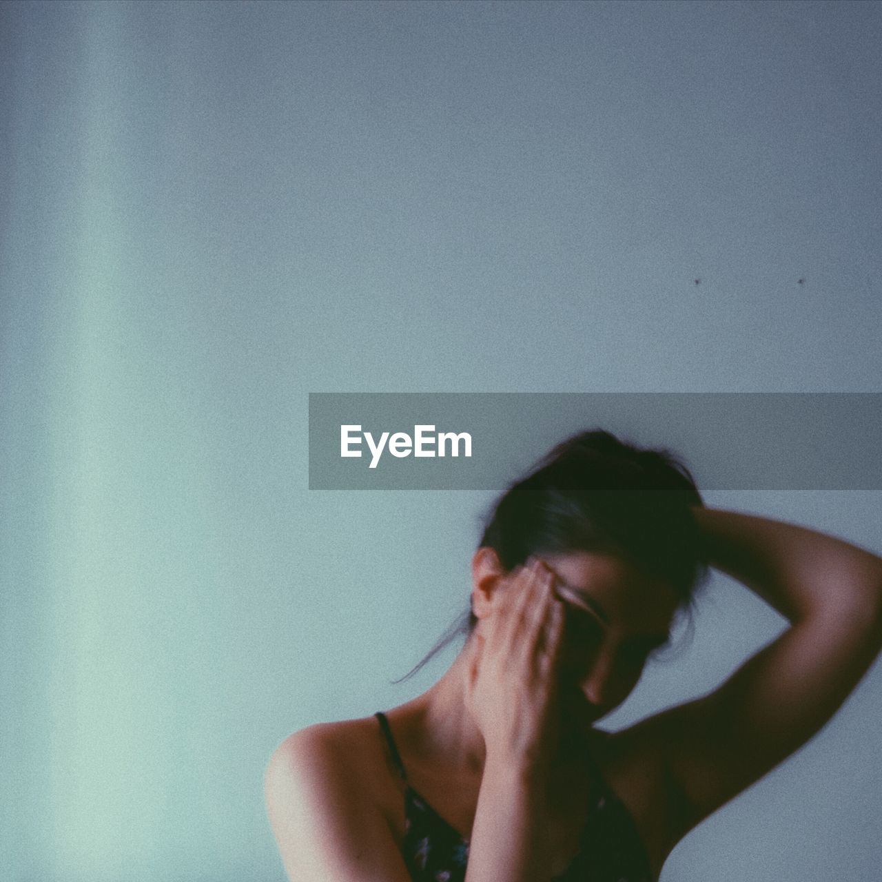 Woman covering face against wall