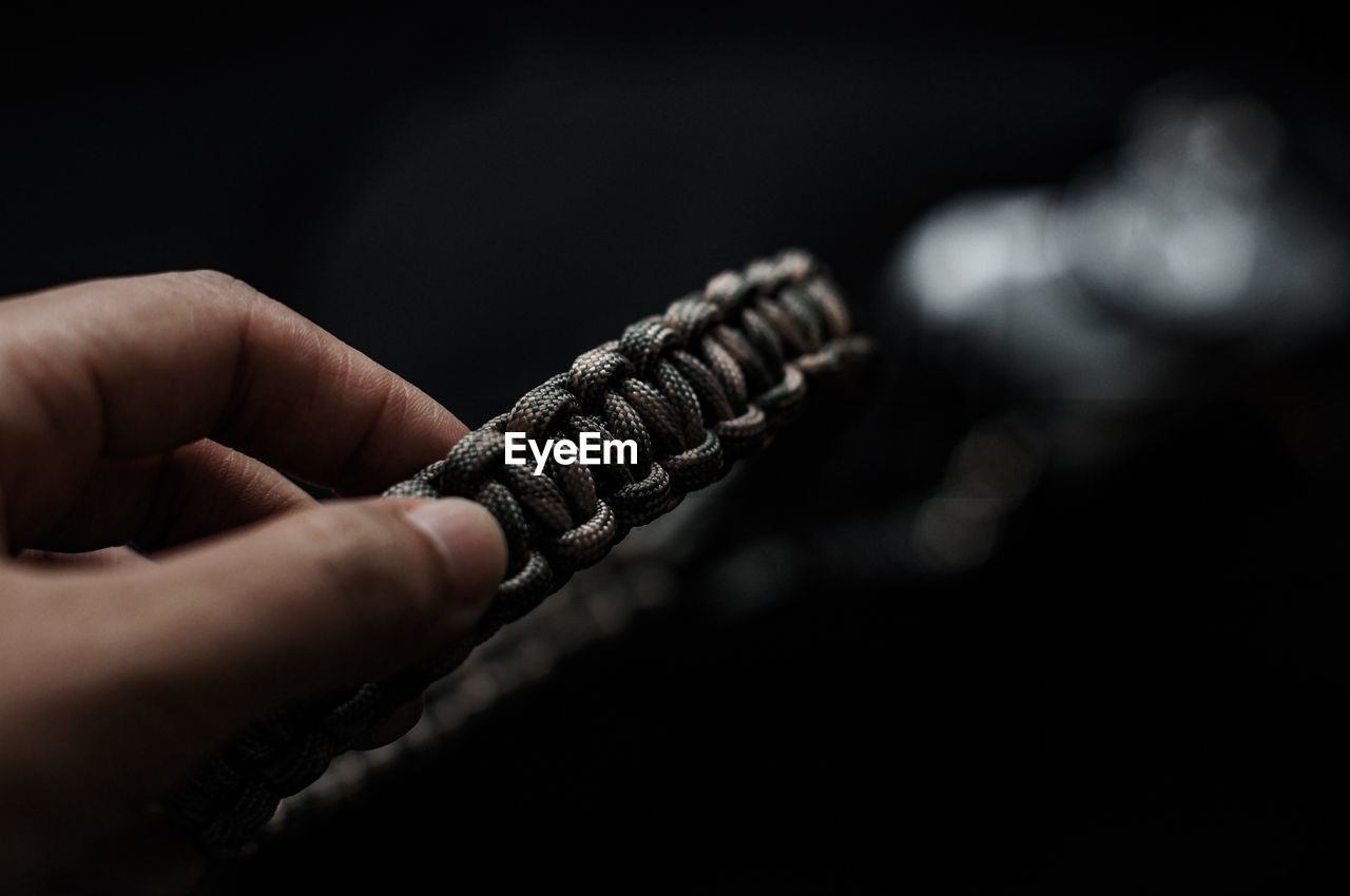 Close-up of hand holding strap against black background