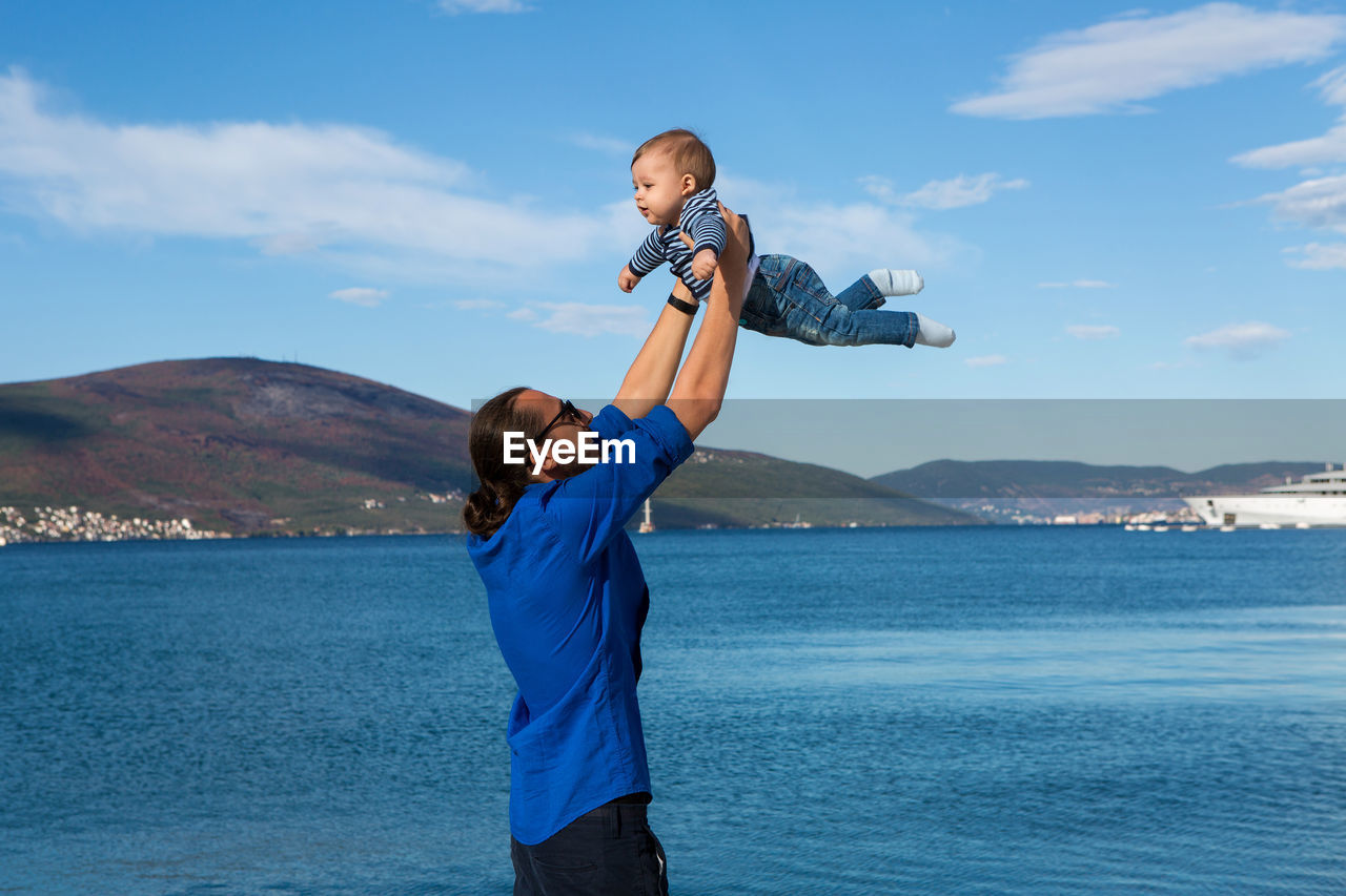 Father raises his son in his arms to the sea in montenegro