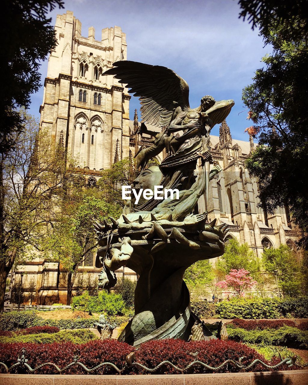 Statue by cathedral of saint john the divine against sky