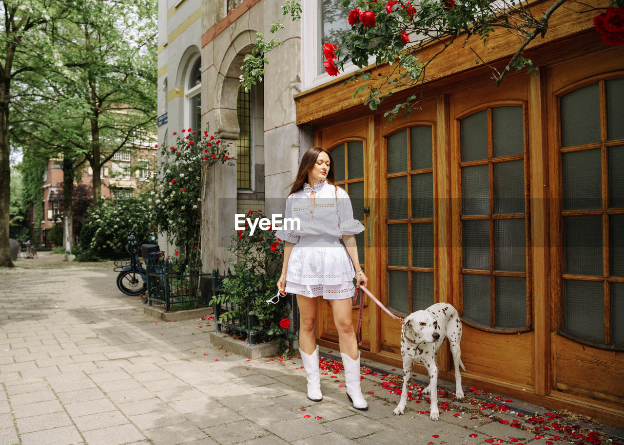 Rear view of woman with dog standing in front of building 