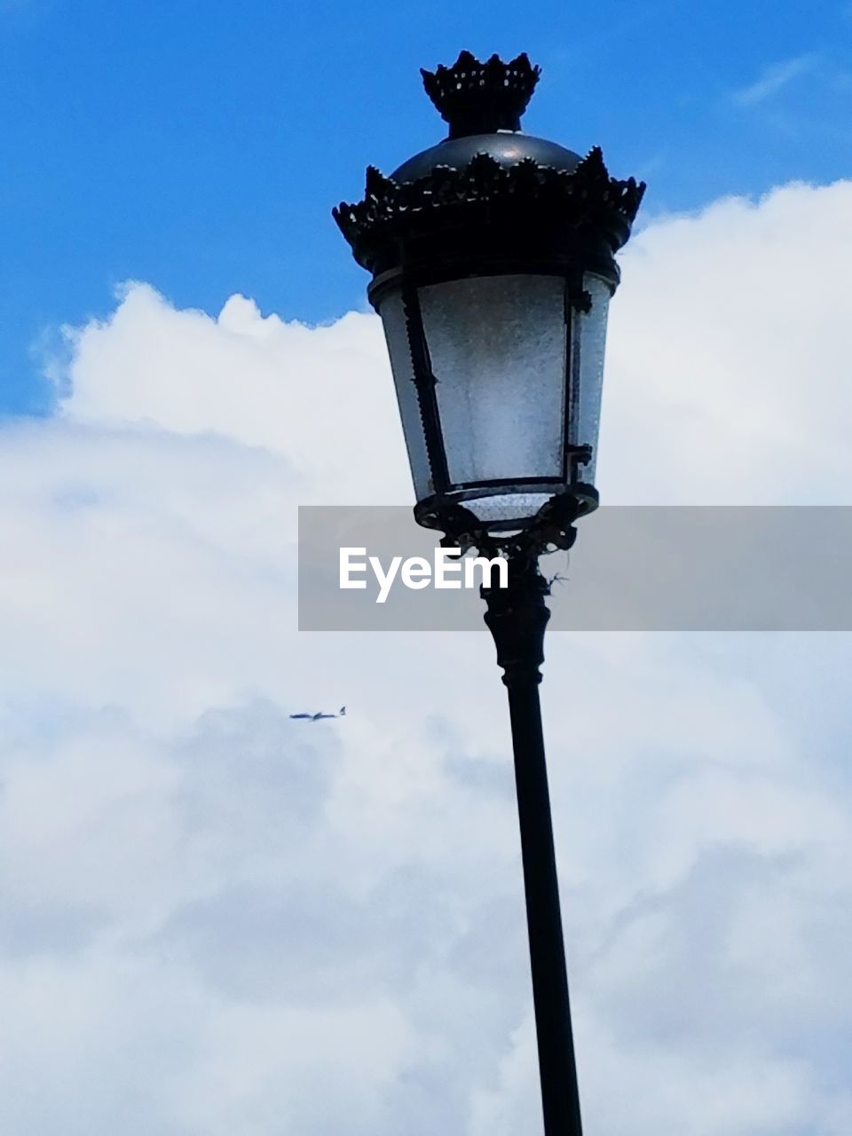 LOW ANGLE VIEW OF STREET LIGHTS AGAINST CLOUDY SKY