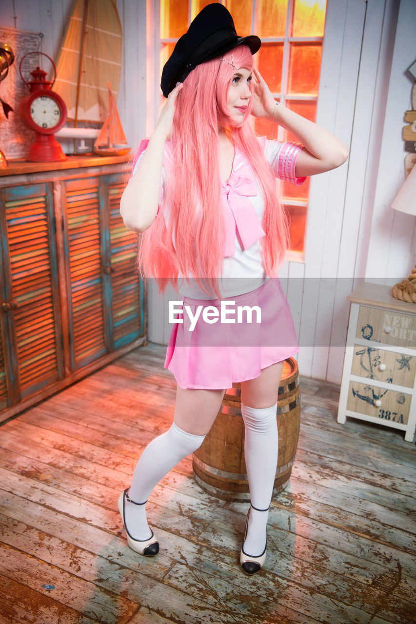 Full length of woman with dyed hair standing on wooden floor at home