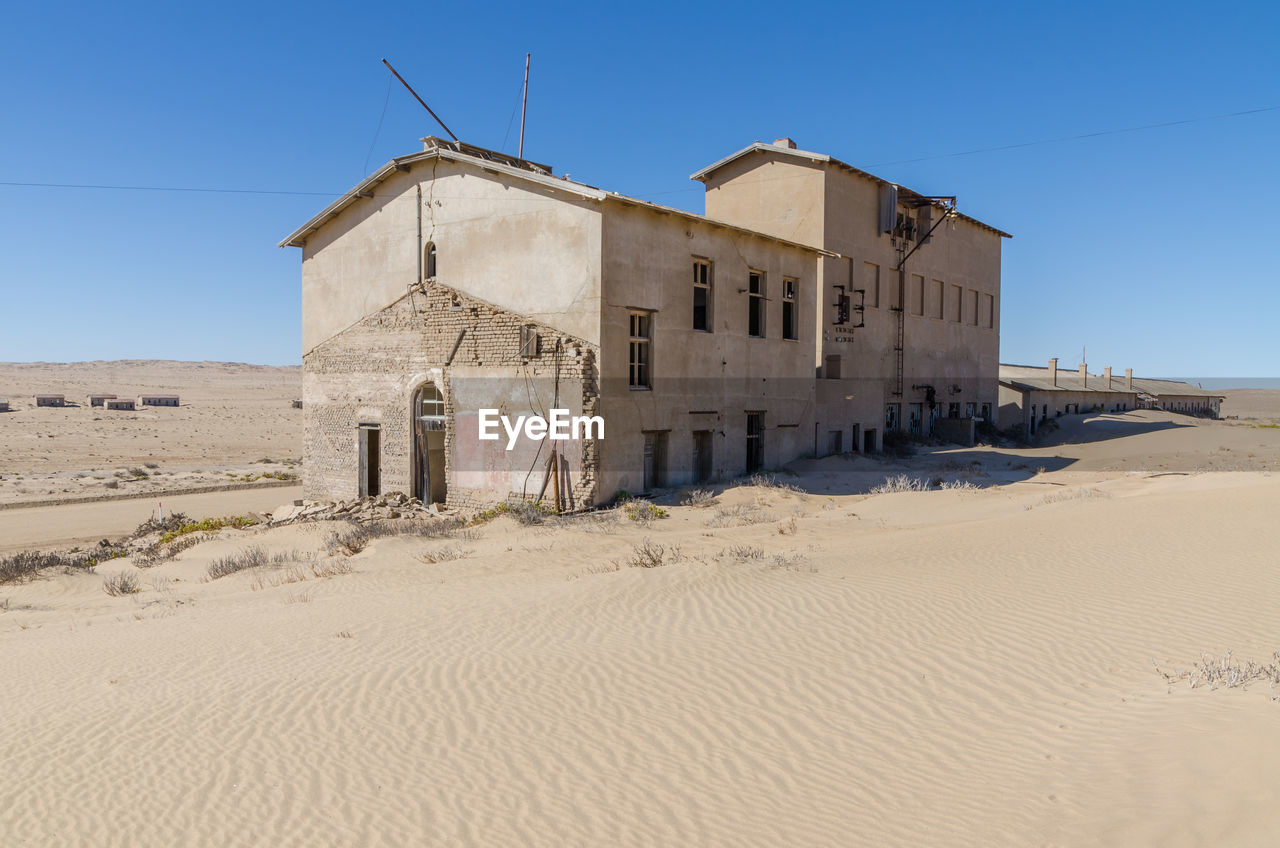 Abandoned buiding on desert against clear blue sky at former german ghost town kolmanskop, namibia