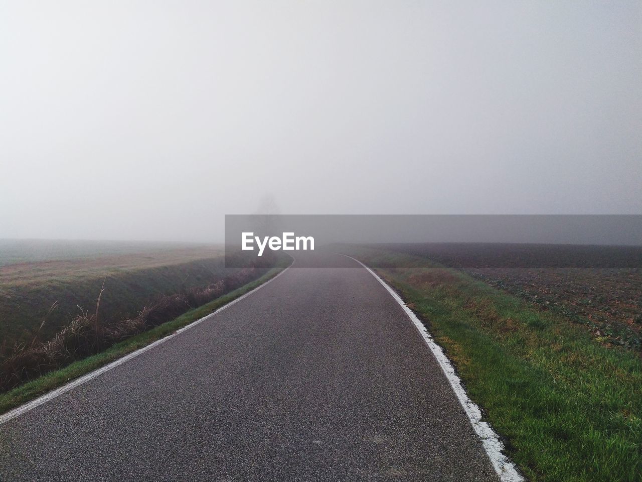 Empty road along landscape against sky