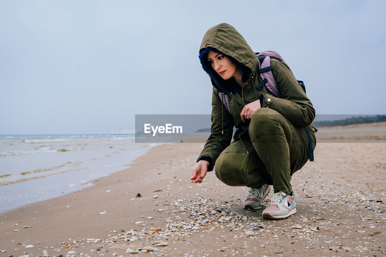 Woman crouching on shore at beach