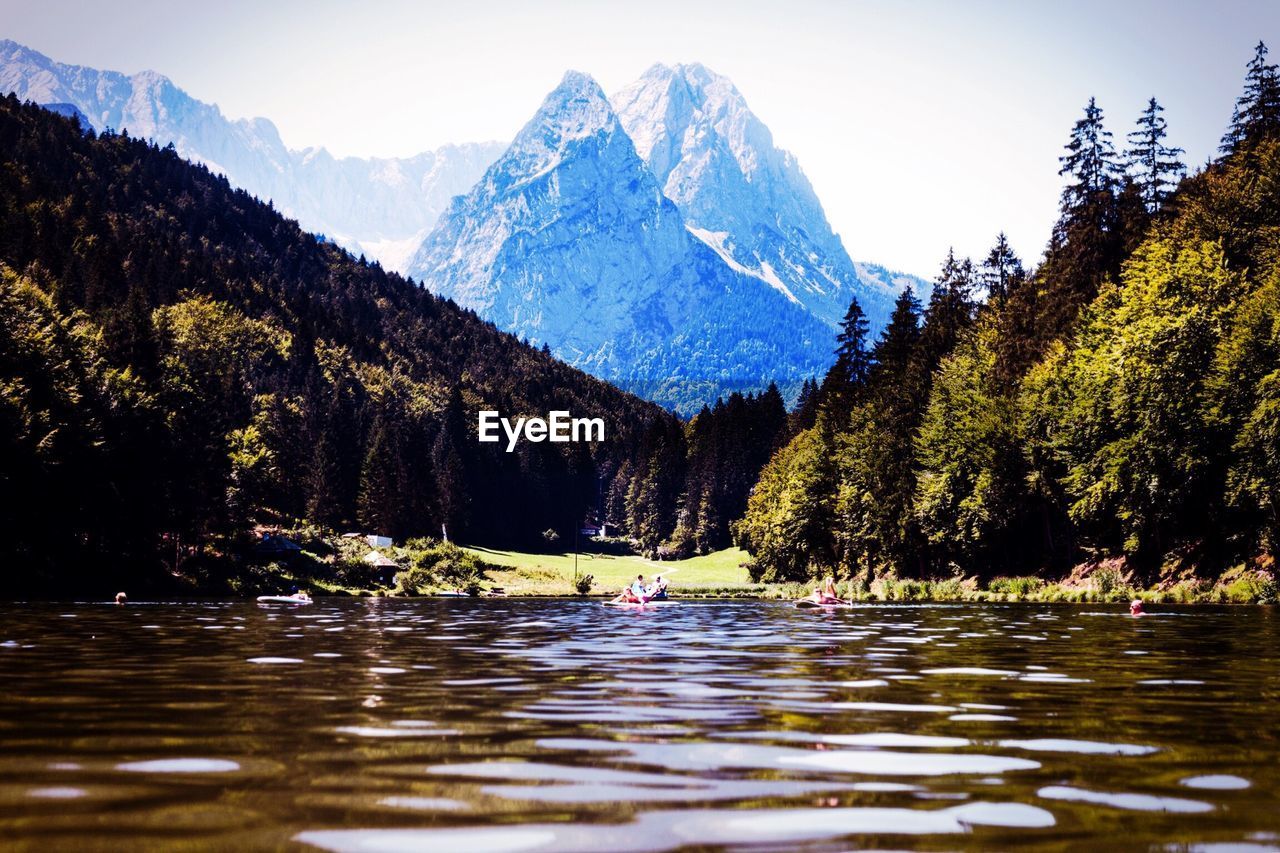 Scenic view of lake by trees with mountains seen in background