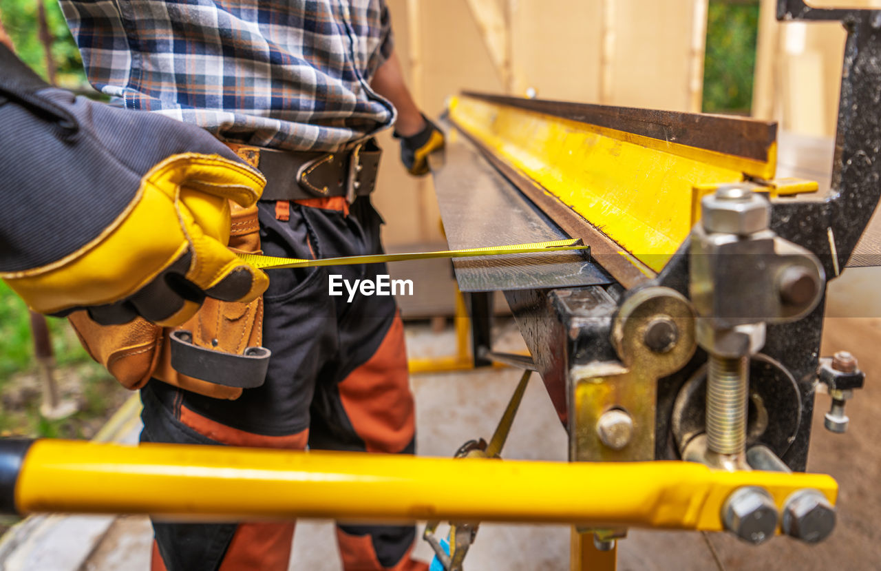 midsection of man working on metal