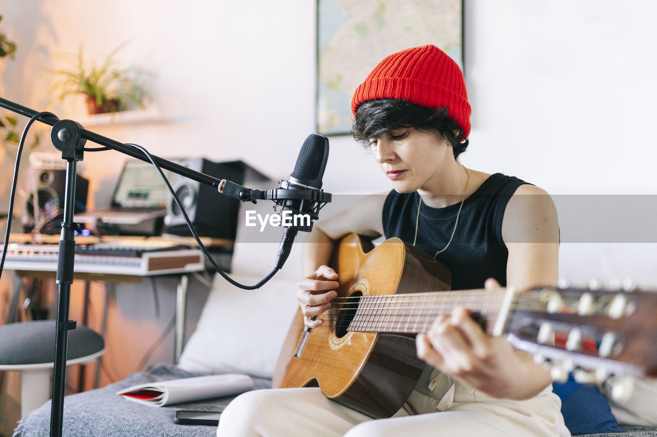 Female guitarist wearing knit hat while playing guitar at studio