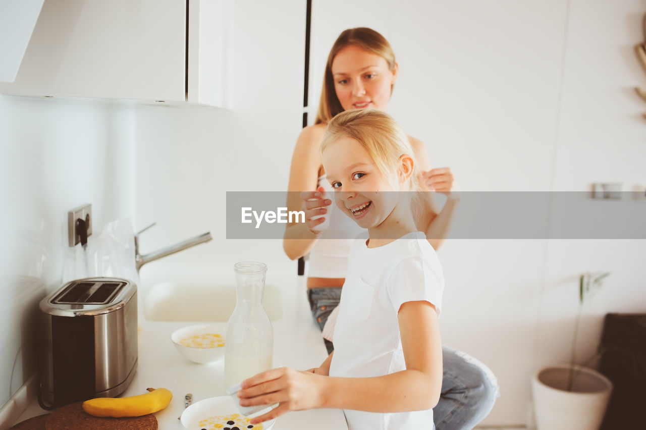 Mother with daughter preparing food in kitchen at home