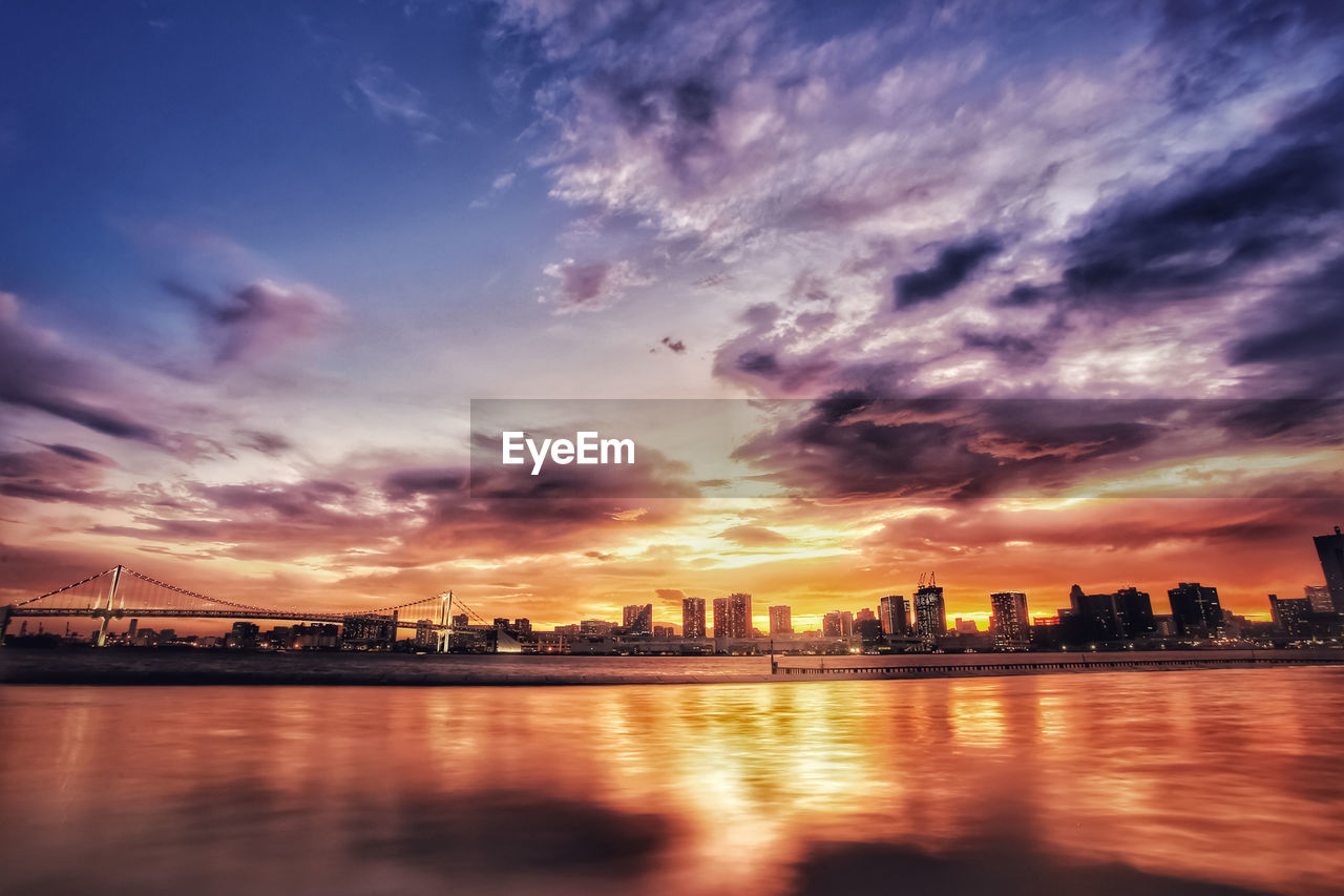 Scenic view of sea by buildings against sky during sunset