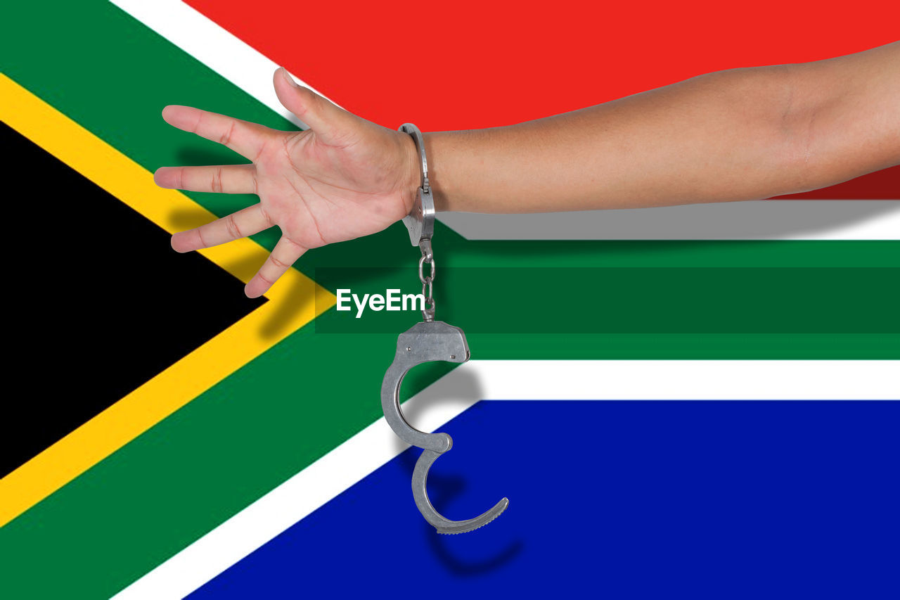 Cropped hand of person wearing handcuffs against south africa flag