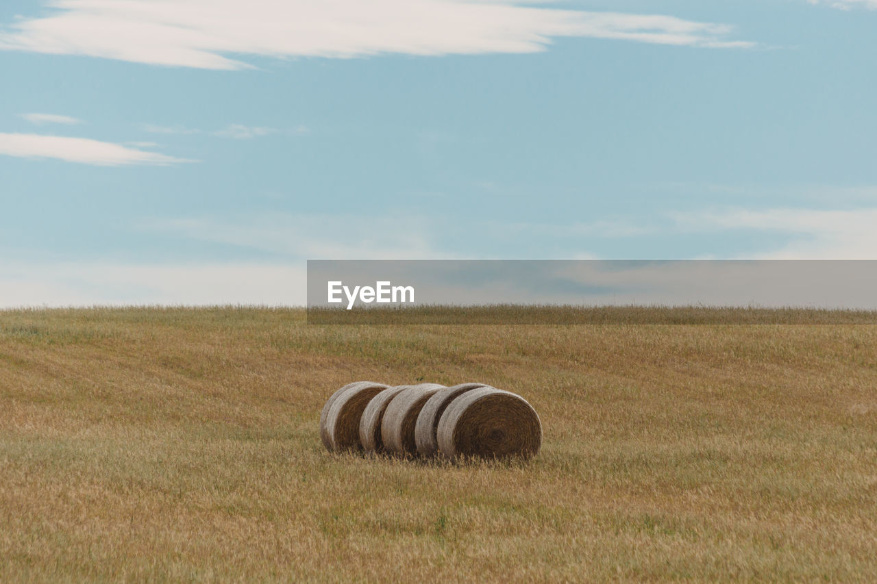 Hay bales on field against sky