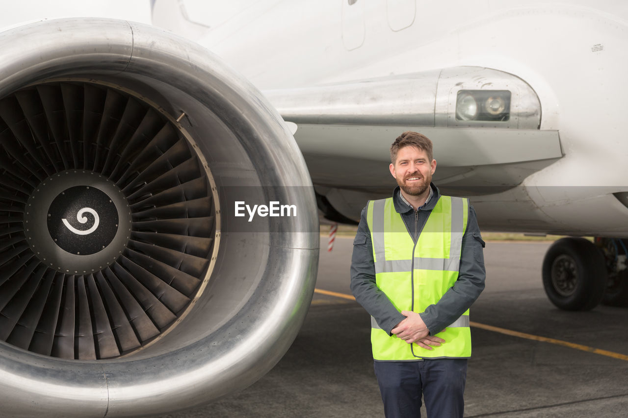 Positive engineer standing near plane