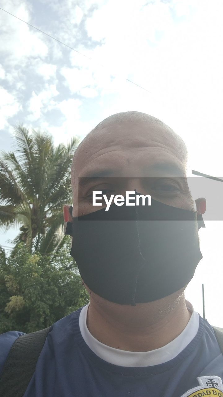 PORTRAIT OF YOUNG MAN WEARING SUNGLASSES AGAINST SKY