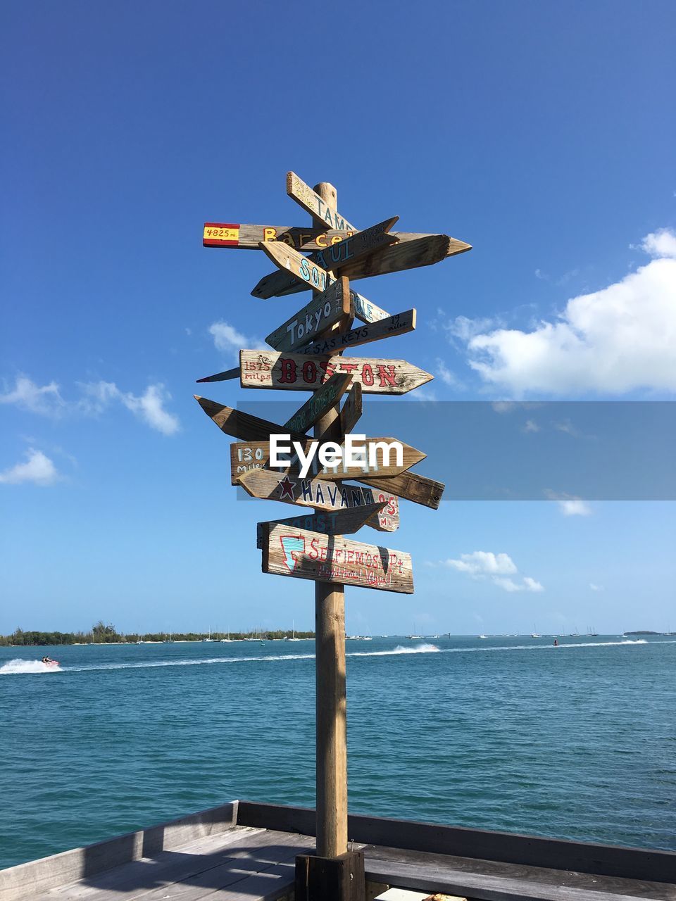 Sign post at sea against blue sky