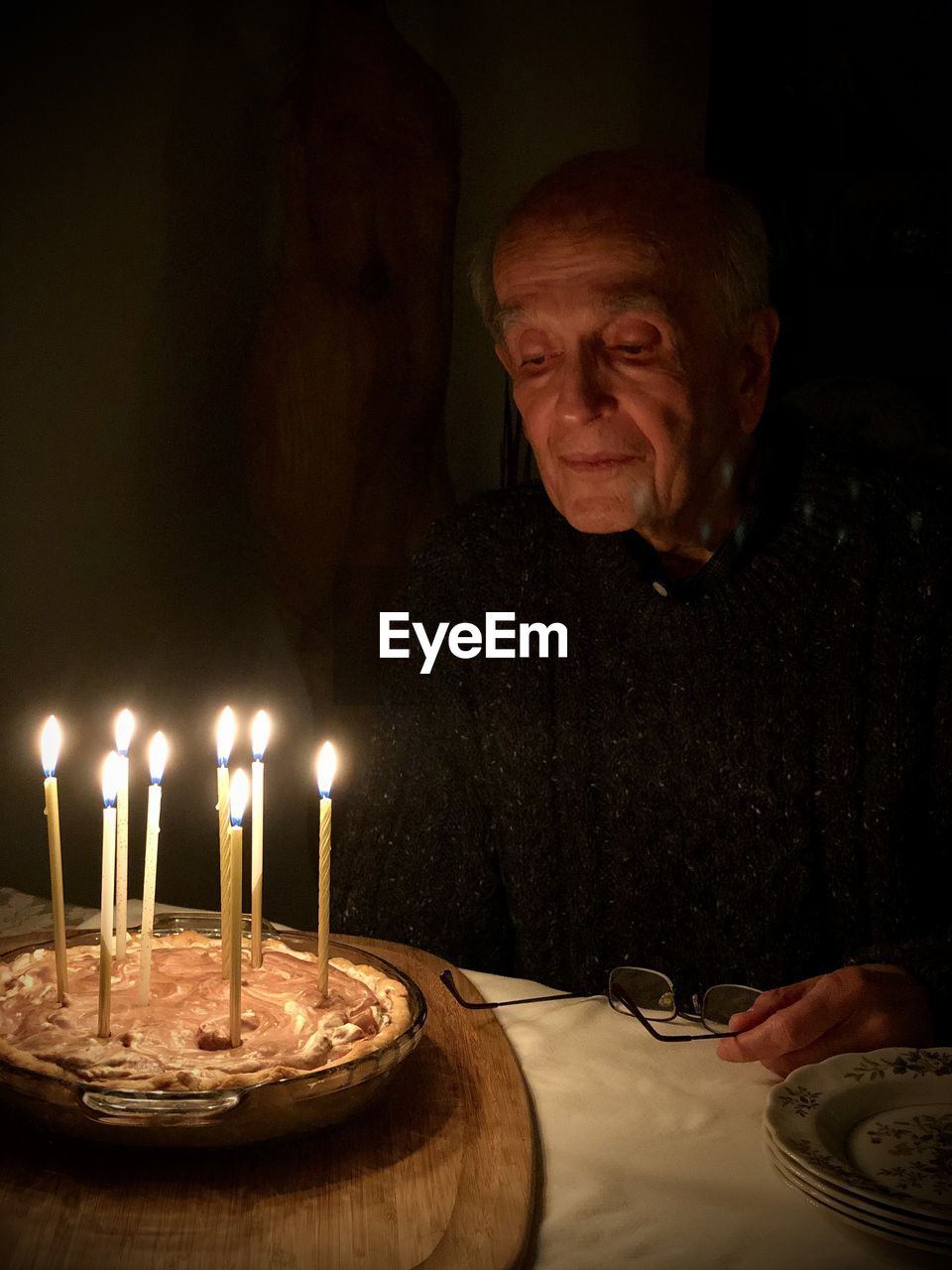 Senior man sitting against cake in darkroom
