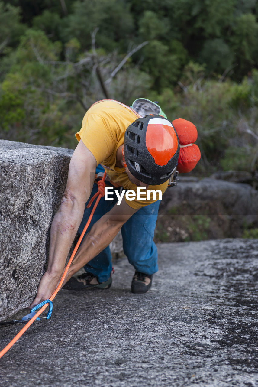 Rock climber looking at his feet while climbing multipitch route