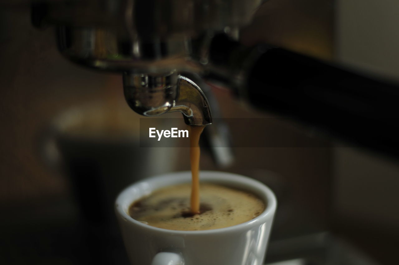 Close-up of machine pouring coffee in cup