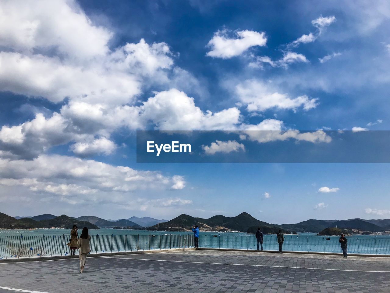 People relaxing on pier against sky
