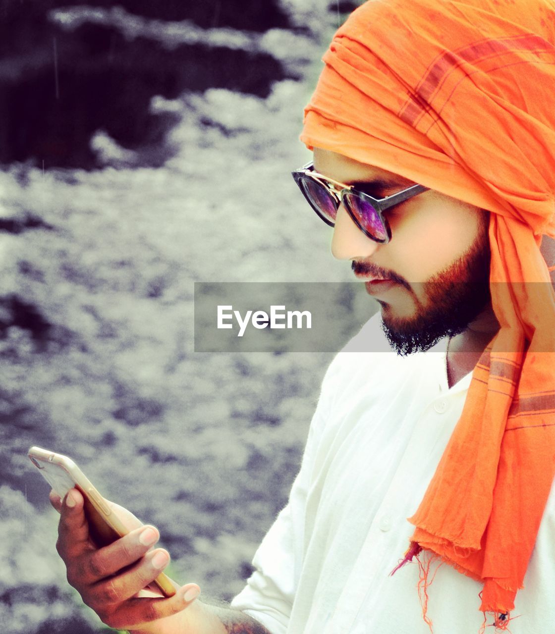 Man in turban and sunglasses using smart phone outdoors
