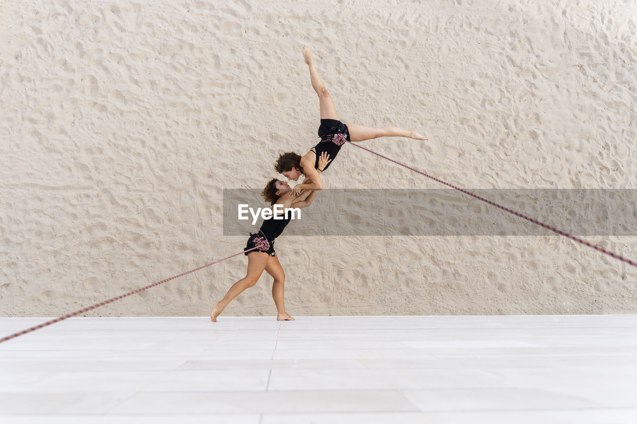 Aerial dancers dancing while hanging against wall
