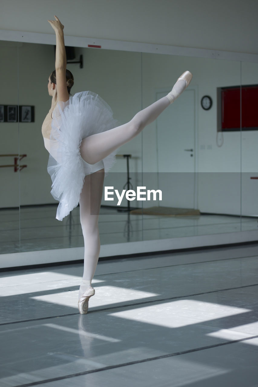 Classical dancer in white tutu dancing in ballet studio