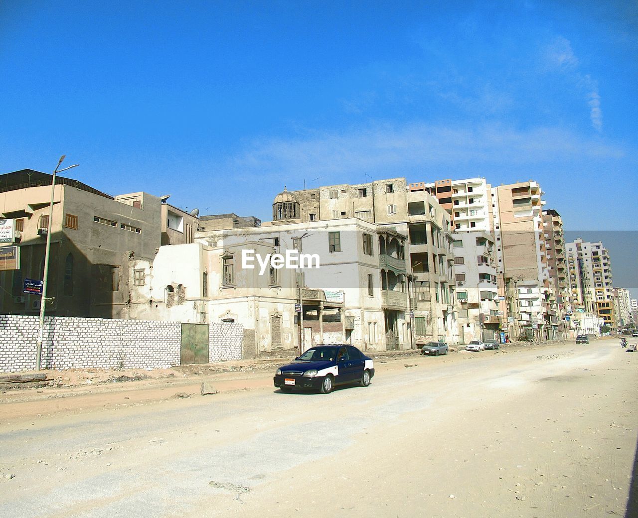 CARS ON ROAD BY BUILDINGS AGAINST SKY