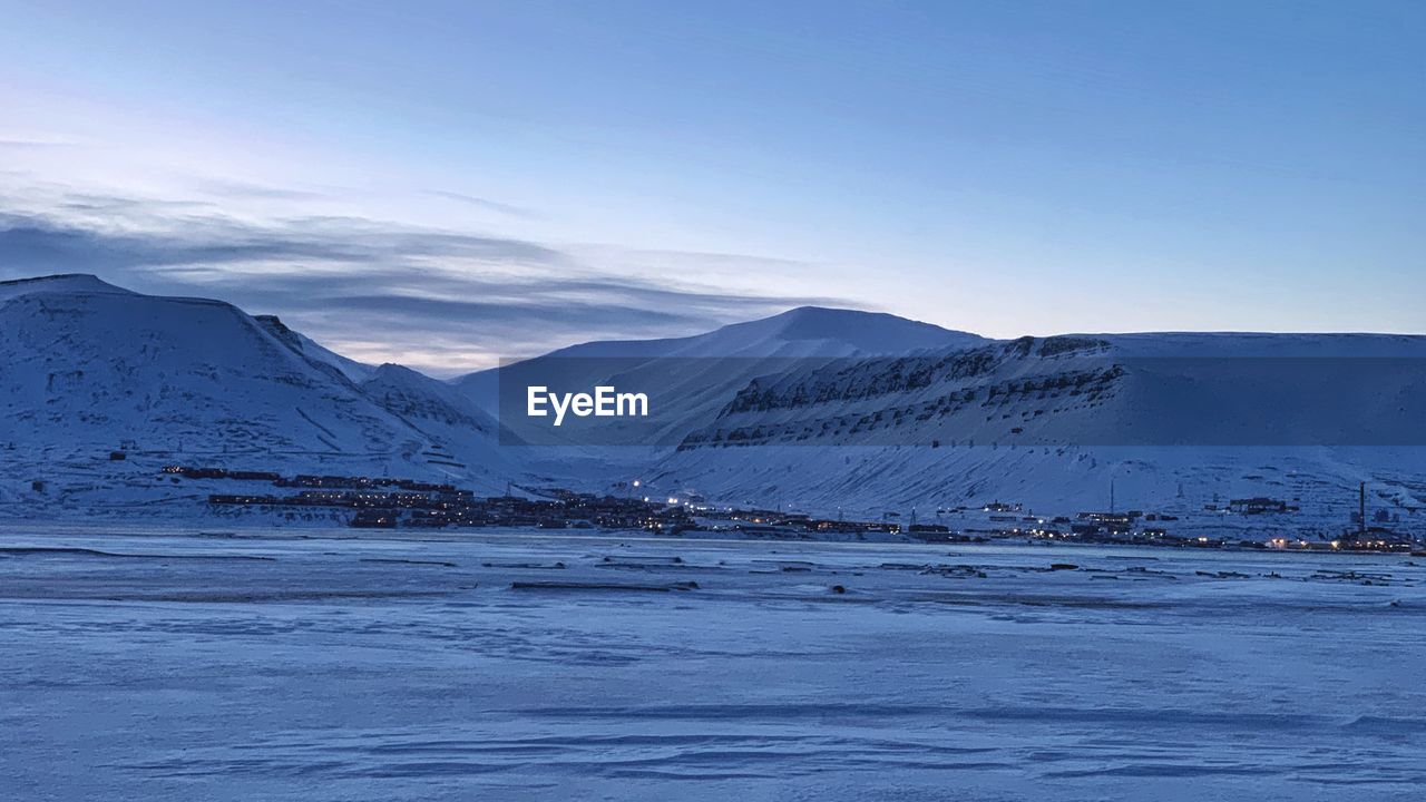 Scenic view of snowcapped mountains by sea against sky