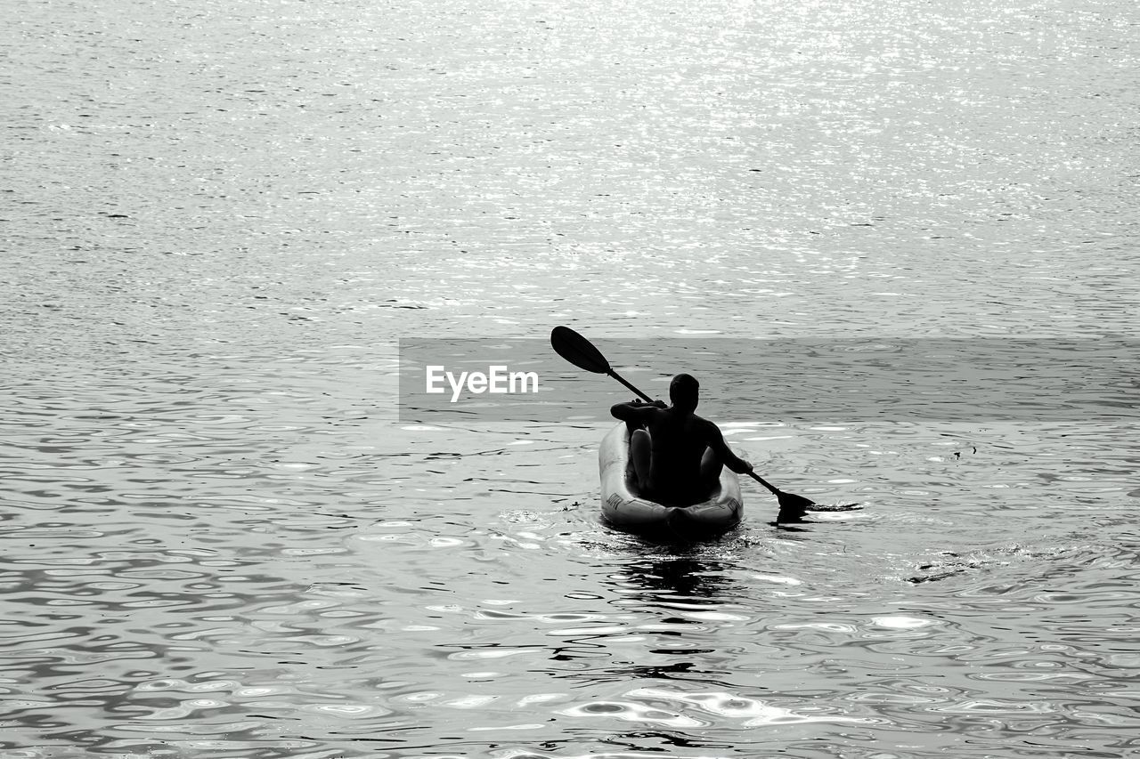 Rear view of man on boat at lake