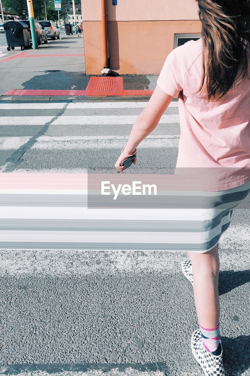 Low section of girl crossing the street 