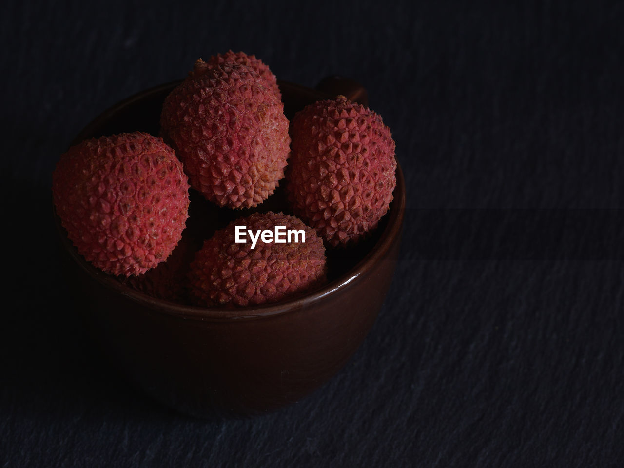 Close-up of lychees in bowl on black background