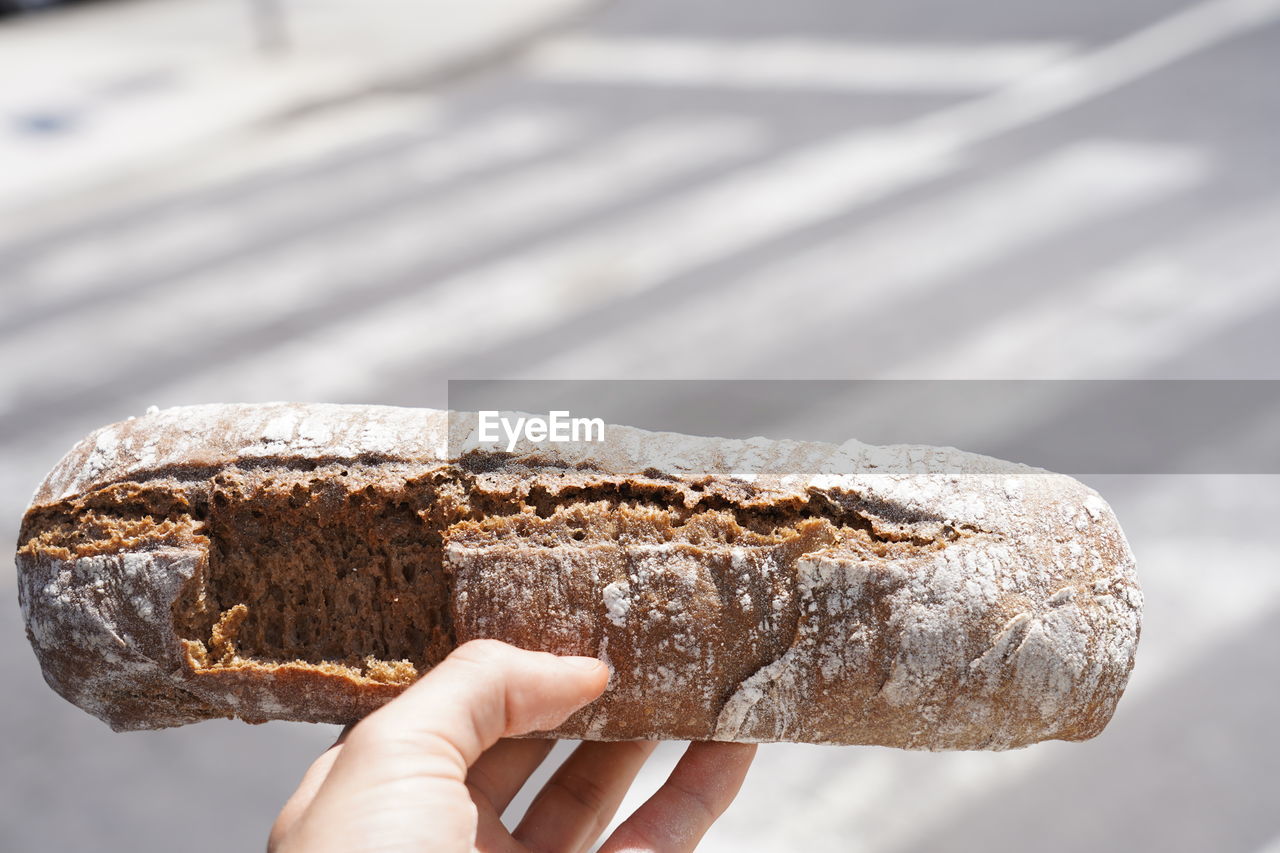 CLOSE-UP OF PERSON HAND HOLDING BREAD