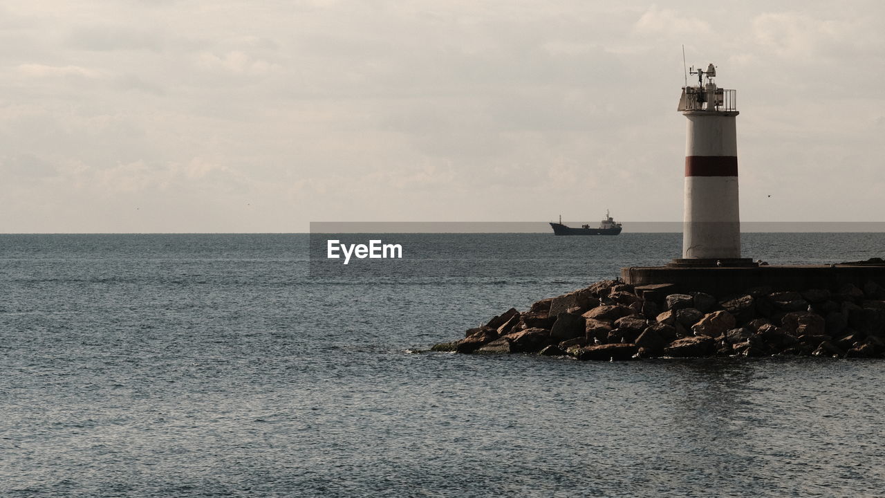 Lighthouse by sea against sky