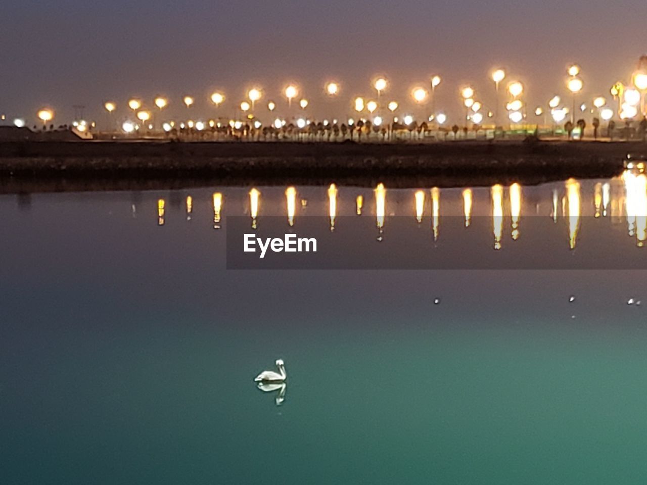 ILLUMINATED PIER OVER LAKE AGAINST SKY AT NIGHT