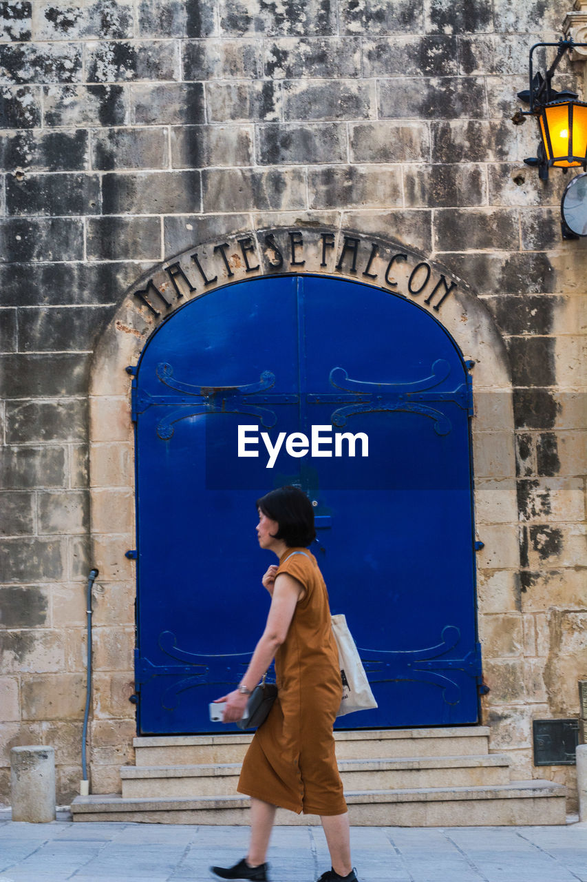 FULL LENGTH OF WOMAN STANDING AGAINST BLUE WALL