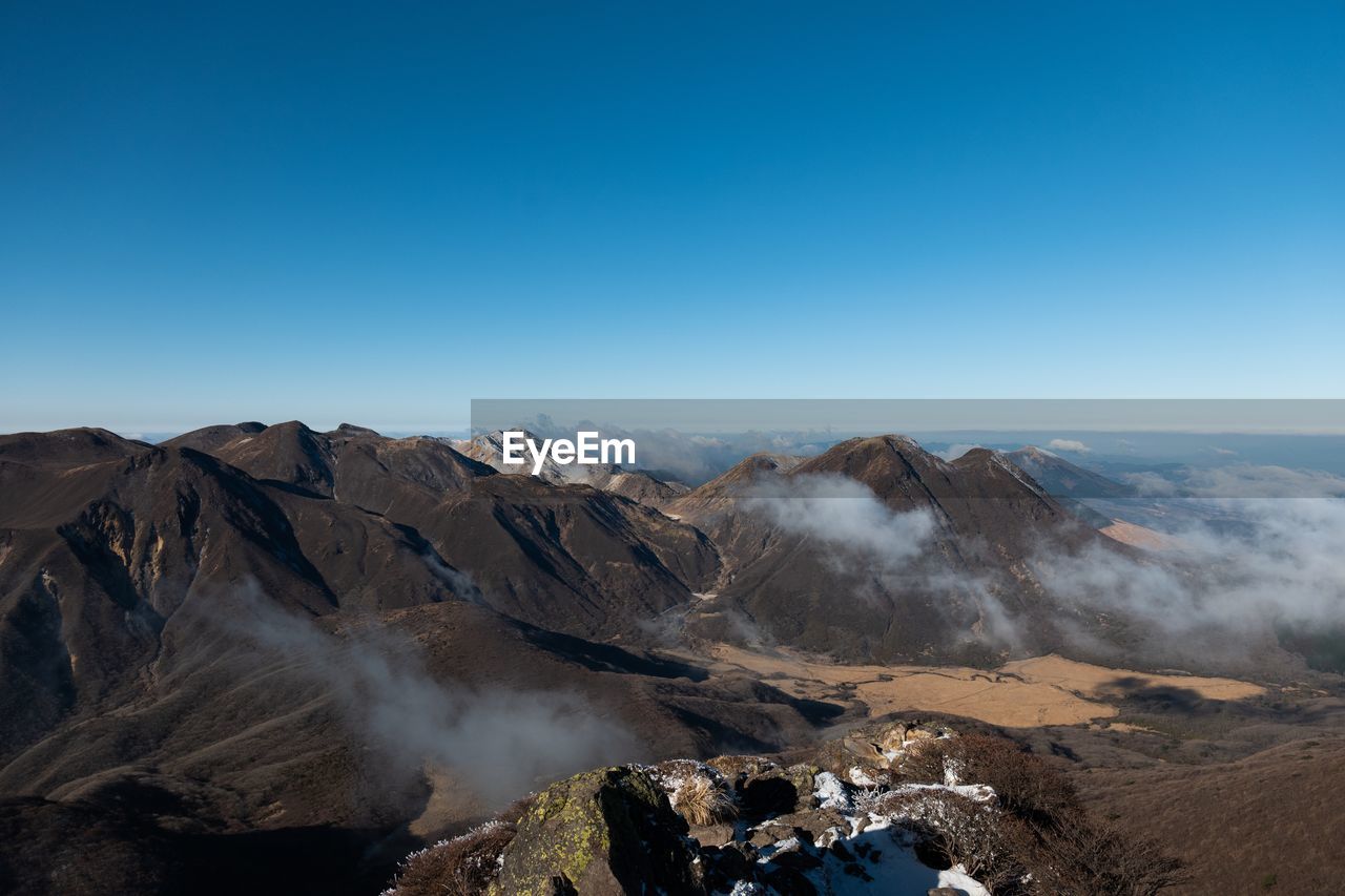PANORAMIC VIEW OF VOLCANIC MOUNTAIN AGAINST BLUE SKY