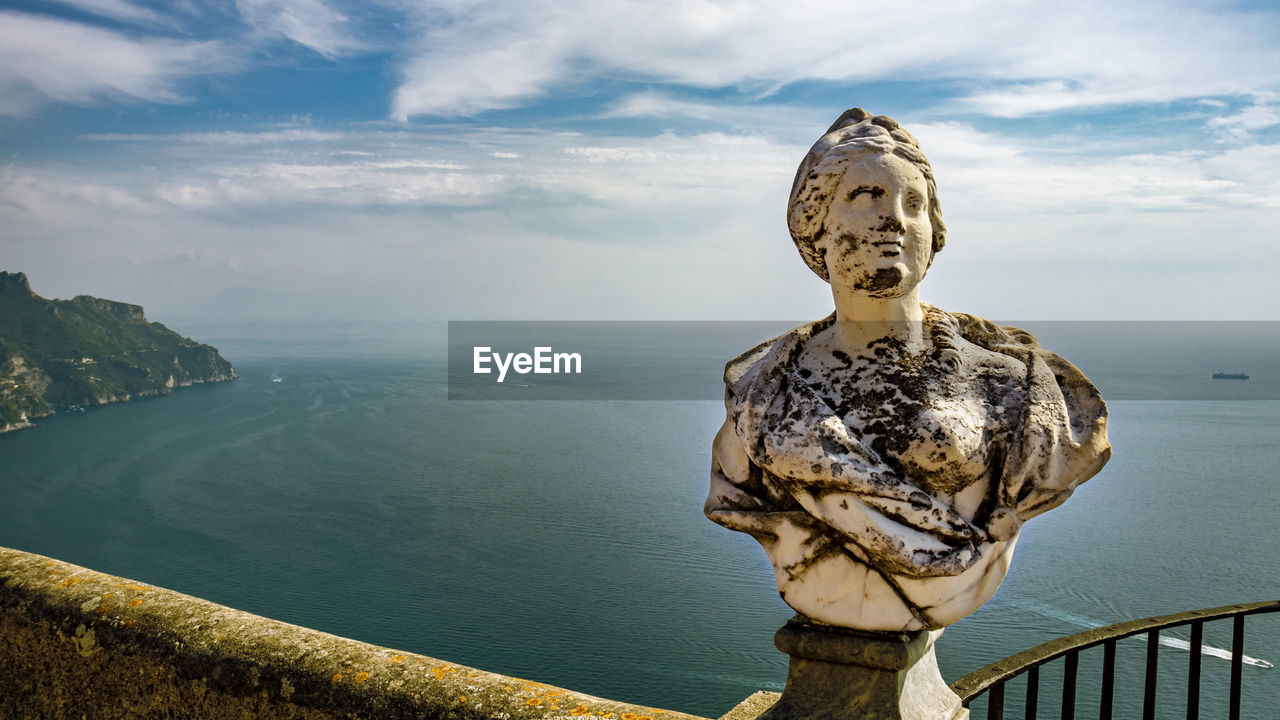 STATUE BY RAILING AGAINST SEA