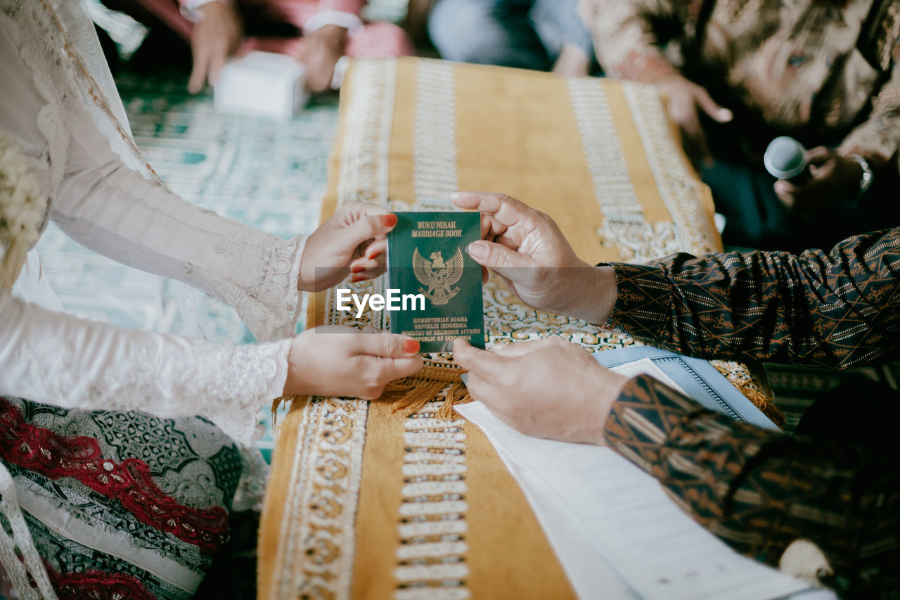 HIGH ANGLE VIEW OF PEOPLE HOLDING HANDS AT THE TABLE