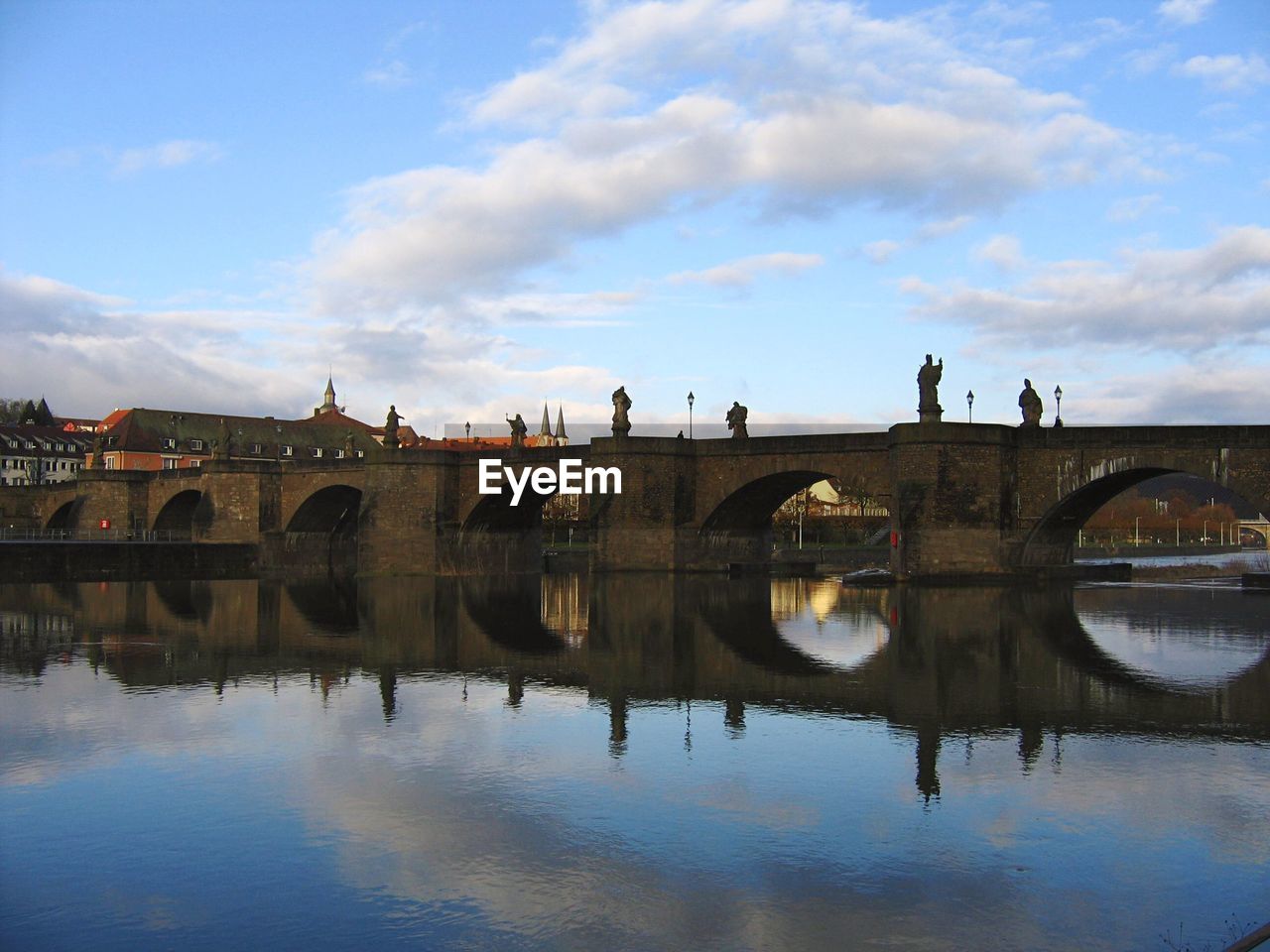 Arch bridge over river against sky in city