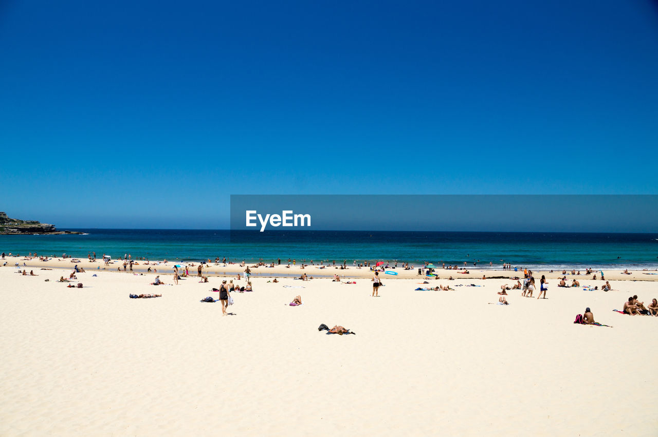 PEOPLE AT BEACH AGAINST CLEAR BLUE SKY