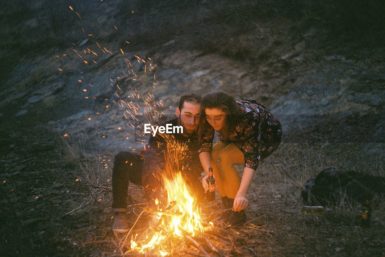 Couple burning campfire at field