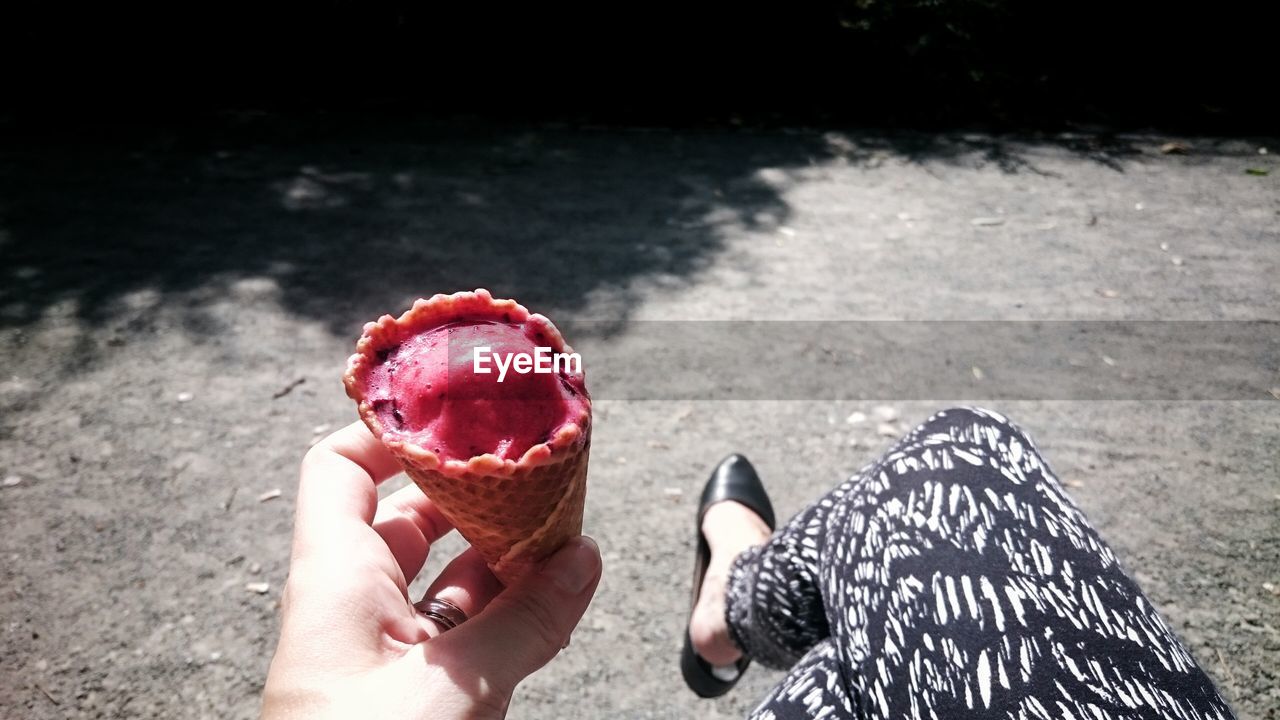 MIDSECTION OF WOMAN HOLDING ICE CREAM CONE OUTDOORS